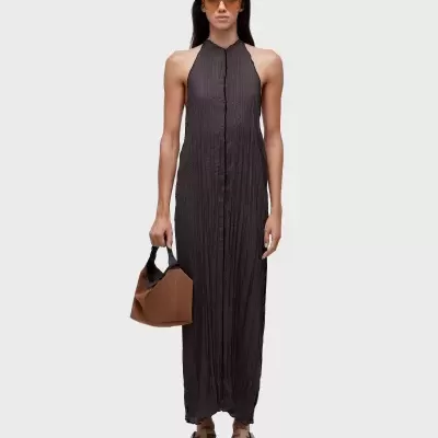 Mulher com vestido preto comprido com textura vincada e mala castanha