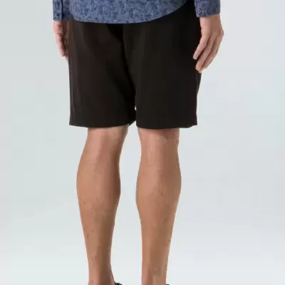 Homem de costas a usar calções pretos e camisa azul com padrão floral.