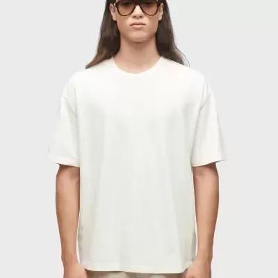 Pessoa com t-shirt branca e calções bege, óculos de sol preta