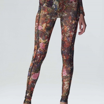 Leggings justas com padrão floral em vários tons, usadas com sandálias brancas.