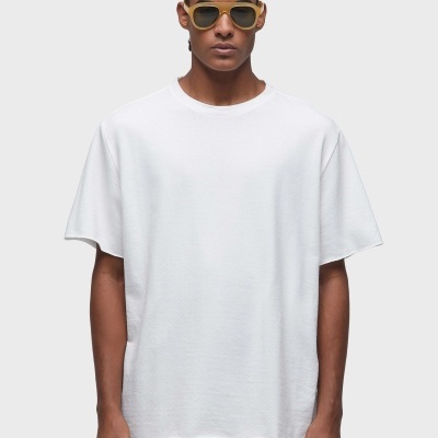 Homem com t-shirt branca, calças castanho claro e óculos de sol amarelos