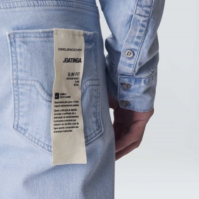 Calças de ganga azul claro com etiqueta e parte da manga do mesmo tecido visível