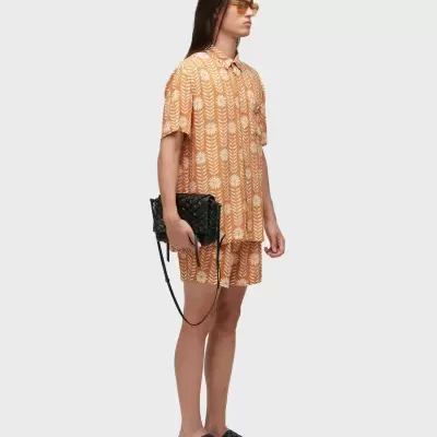 Homem com roupa laranja estampada e acessórios pretos