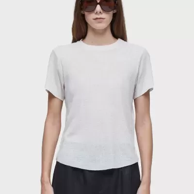 Mulher com t-shirt branca de manga curta e calças pretas com óculos de sol castanhos