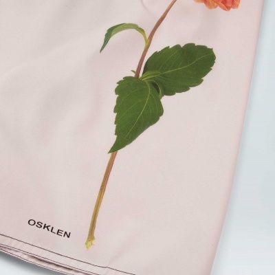 Pano rosa claro com flor vermelha-laranja impressa e marca OSKLEN