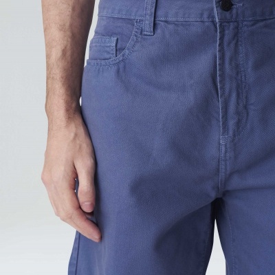 Calções de tecido azul com bolso e botão preto, usados por homem
