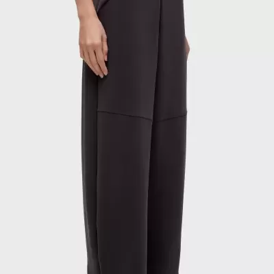 Calças largas pretas com bolso lateral e costura horizontal, usadas com sapatilhas brancas