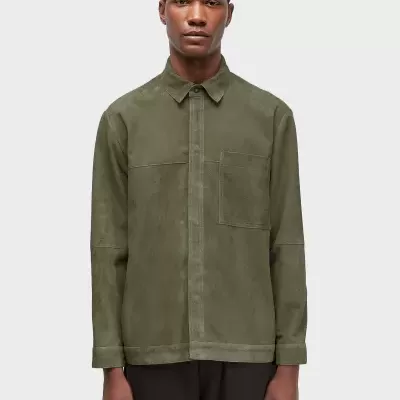 Camisa de camurça verde militar com bolso frontal usada por modelo com calças pretas.