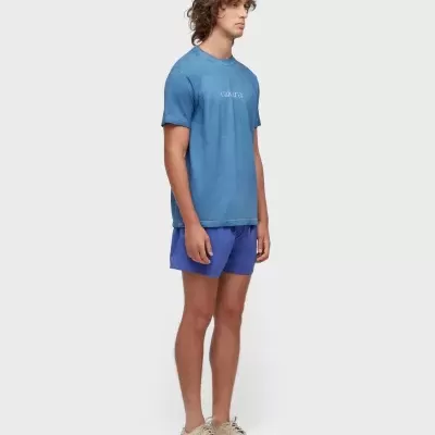 Homem vestido com camisola azul, calções azuis e ténis bege