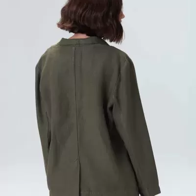 Blazer verde-oliva de mulher visto de costas em fundo neutro