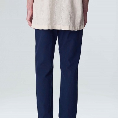 Calças azuis escuras de corte reto com camiseta bege clara e sapatos pretos em fundo cinza claro