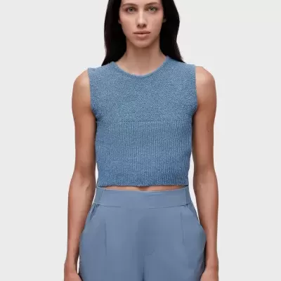 Mulher com top azul de malha e calções azuis claros.