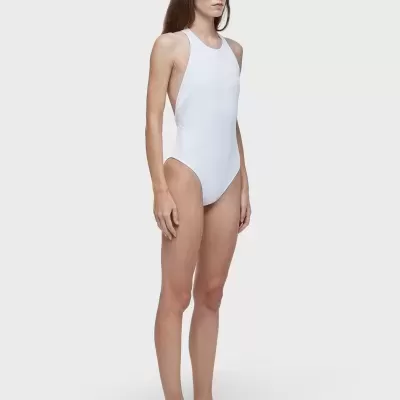 Modelo com fato de banho branco, óculos escuros e ténis brancos