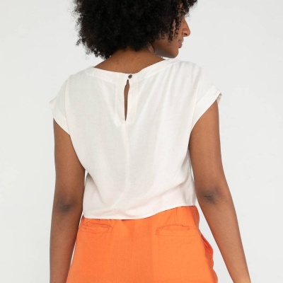 Top branco de manga curta e calções laranja vistos pelas costas