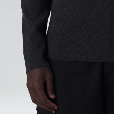 Parte do corpo com camisola cinza escura e calças pretas, texturas lisas.