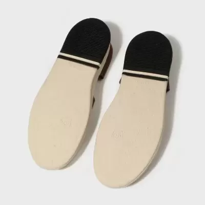 Solas de sapatos bege com salto preto e linha branca sobre fundo branco