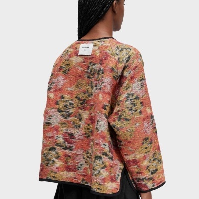 Camisola comprida com padrão floral vermelho e amarelo com etiqueta branca OSKLEN na parte de trás.