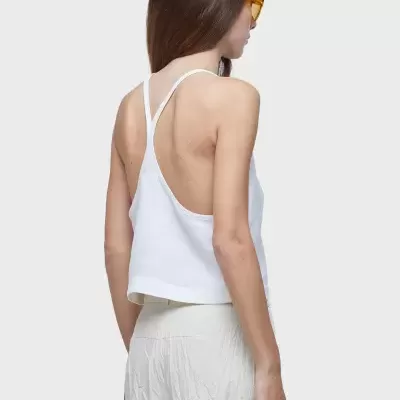 Top feminino branco com alças finas cruzadas nas costas e calças brancas texturizadas