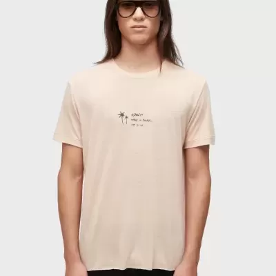 T-shirt bege clara com pequena estampa de palmeiras e texto preto no peito