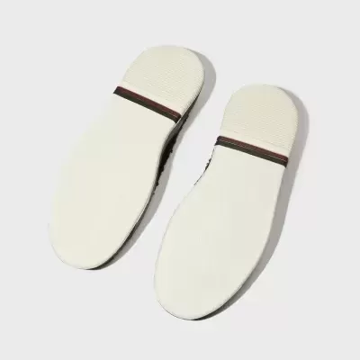 Solas de calçado brancas com faixa preta e vermelha sobre fundo cinza