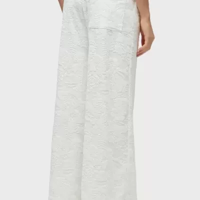 Calças brancas com padrão floral em relevo e bolso traseiro