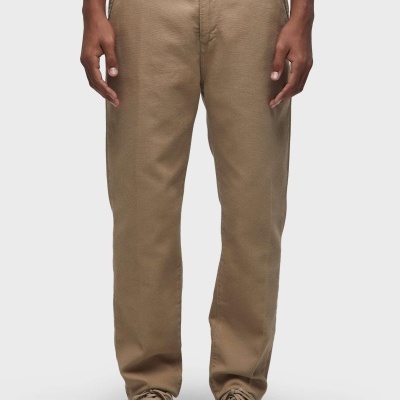 Calças castanhas com textura lisa, modelo com sapatilhas castanhas e t-shirt branca.