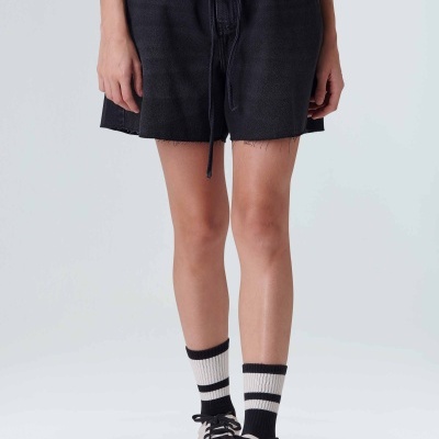 Falda preta com cintura elástica e cordão, meias brancas com riscas pretas e sapatilhas brancas com atacadores pretos.