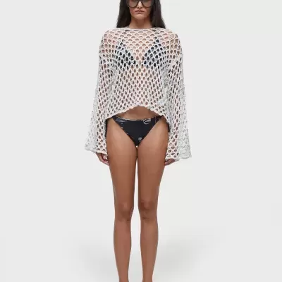 Mulher com capa de malha branca e bikini preto com padrão