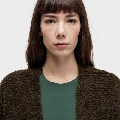 Mulher com camisola verde e casaco castanho de malha grosso