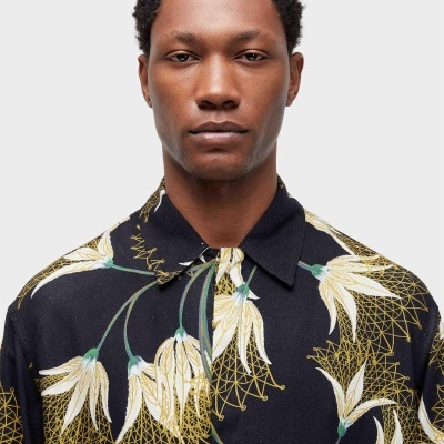 Homem com camisa preta de padrão floral, fundo branco