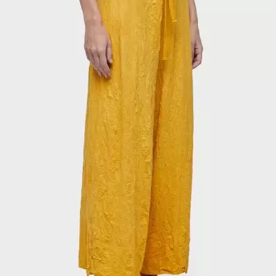 Calças amarelas largas com padrão floral em relevo e cordão na cintura