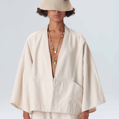 Pessoa com chapéu bucket bege, casaco largo tipo kimono e colares dourados