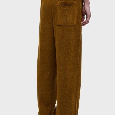 Calças largas castanho-avermelhado em tecido felpudo com bolso quadrado atrás e tênis brancos com padrão floral.