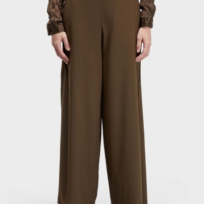Pantalonas castanhas largas com camisa castanha texturada e sandálias castanhas.