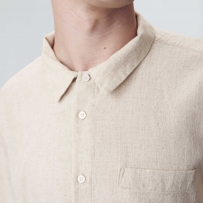Camisa bege clara de manga curta com botões e bolso no peito