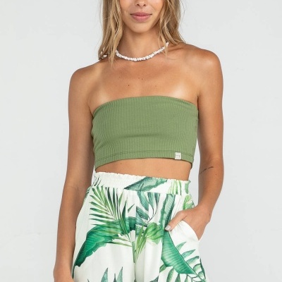 Mulher com top cropped verde oliva e calções brancos com estampa de folhas verdes