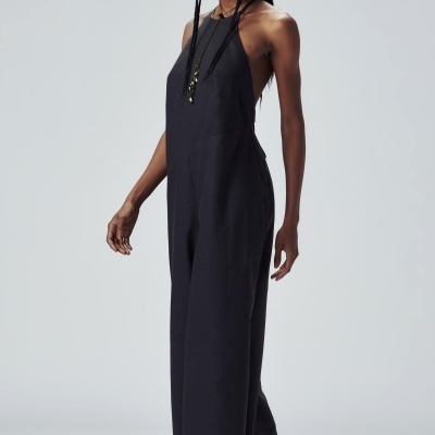 Macacão preto sem mangas feminino com sandálias e óculos de sol, fundo claro