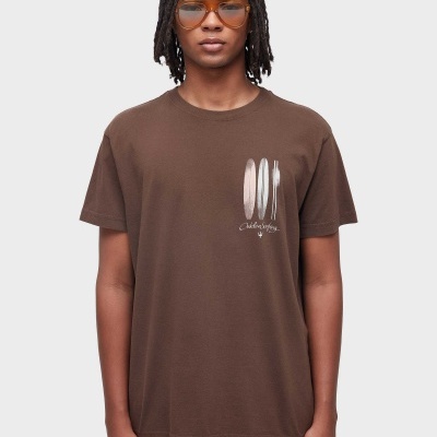 T-shirt castanha com estampa frontal de pranchas de surf e texto em branco.