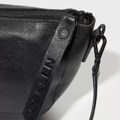 Mala preta em pele com fecho de correr e aba lateral com a palavra CALVIN