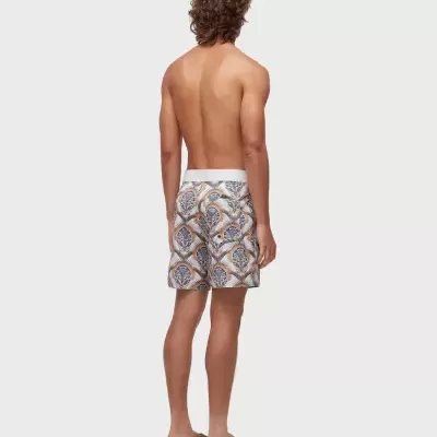 Homem de costas com calções de banho florais e sandálias castanhas