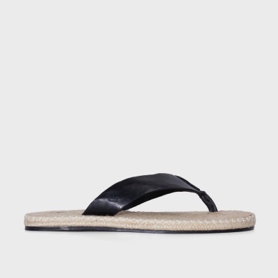 Chinelo flip-flop com base bege e tiras pretas sobre fundo cinzento