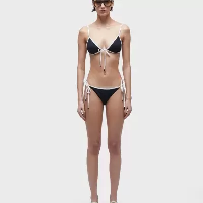 Biquíni feminino preto com detalhes em branco, chinelos brancos e óculos escuros