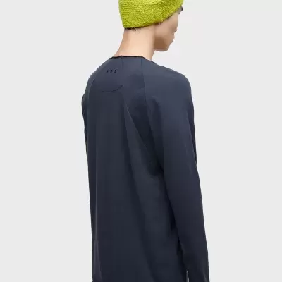 Modelo de costas com camisola azul escura, calças castanhas e gorro verde limão