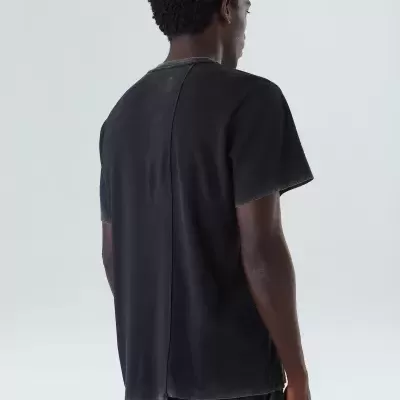 Camiseta preta de costas com costura central vertical e pequeno rasgo na bainha.