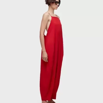 Macacão largo vermelho com alças finas, costas abertas e sapatos marrons