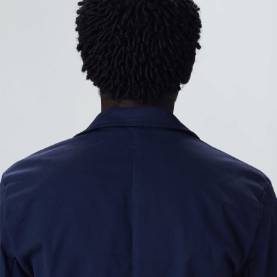 Pessoa de costas com casaco azul escuro em fundo cinzento