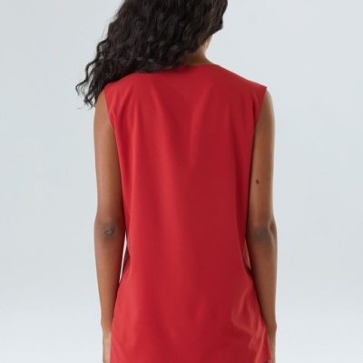 Top feminino vermelho sem mangas visto pelas costas em fundo cinzento claro