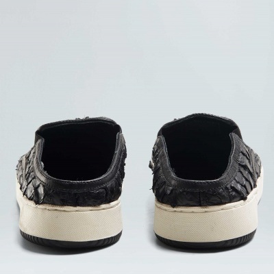 Par de ténis pretos com sola branca e textura escamosa vistos de trás