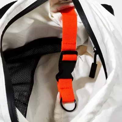 Interior de mochila branca com alça vermelha e bolso em malha preta