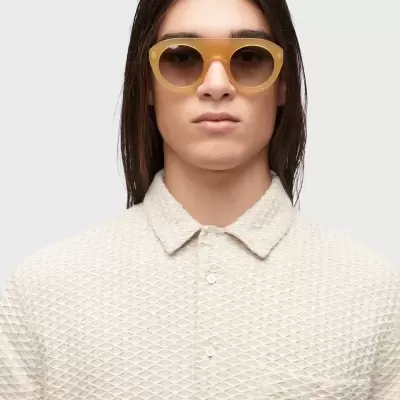 Óculos de sol amarelos com lentes escuras e camisa bege texturada